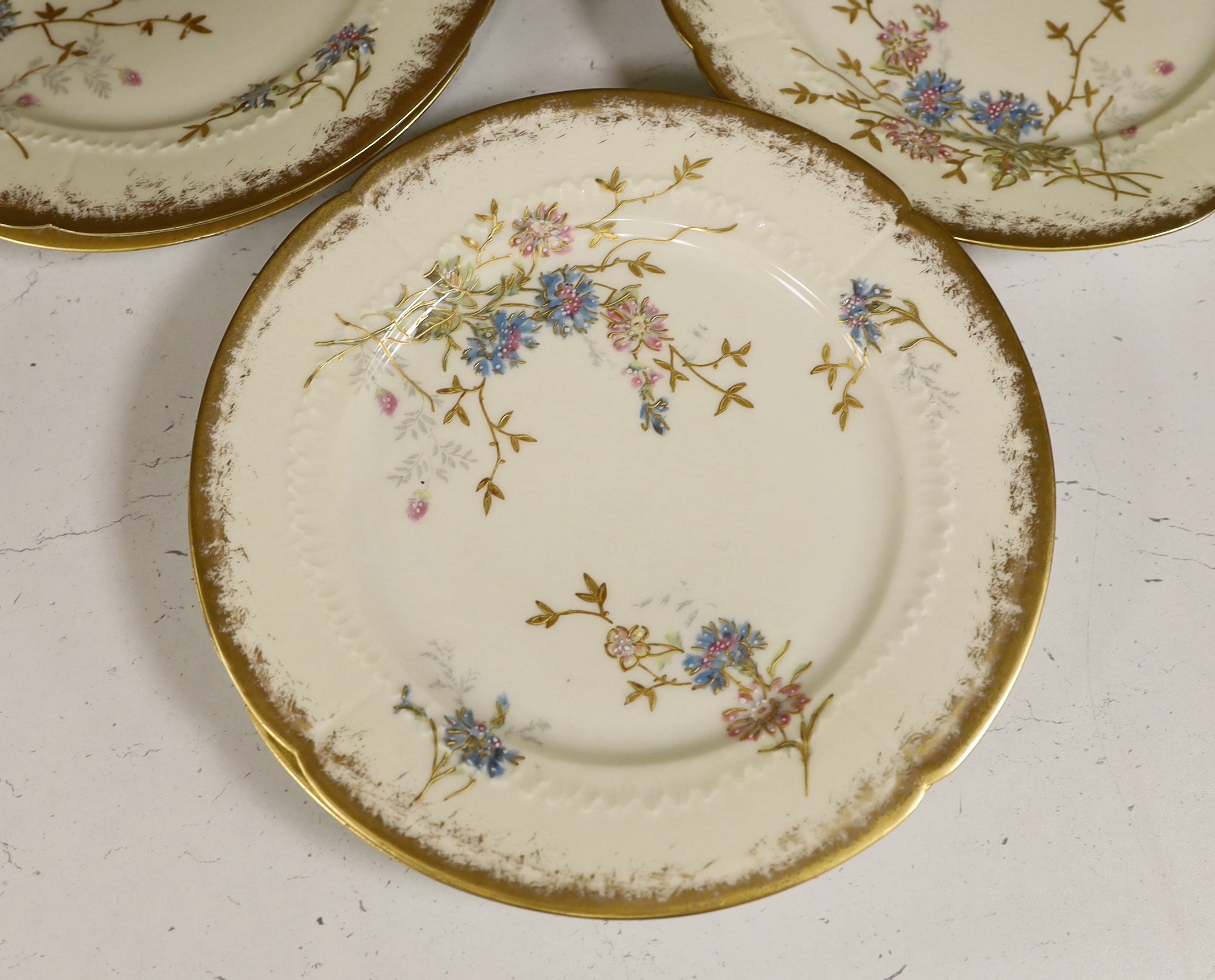 Thirteen Limoges style porcelain dessert plates, two on pedestal bases, gilt decorated with cornflowers etc., 24.5cm diameter